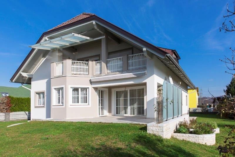 Modernes Haus mit großem Garten und Balkon, umgeben von grüner Landschaft und viel Platz zum Entspannen.